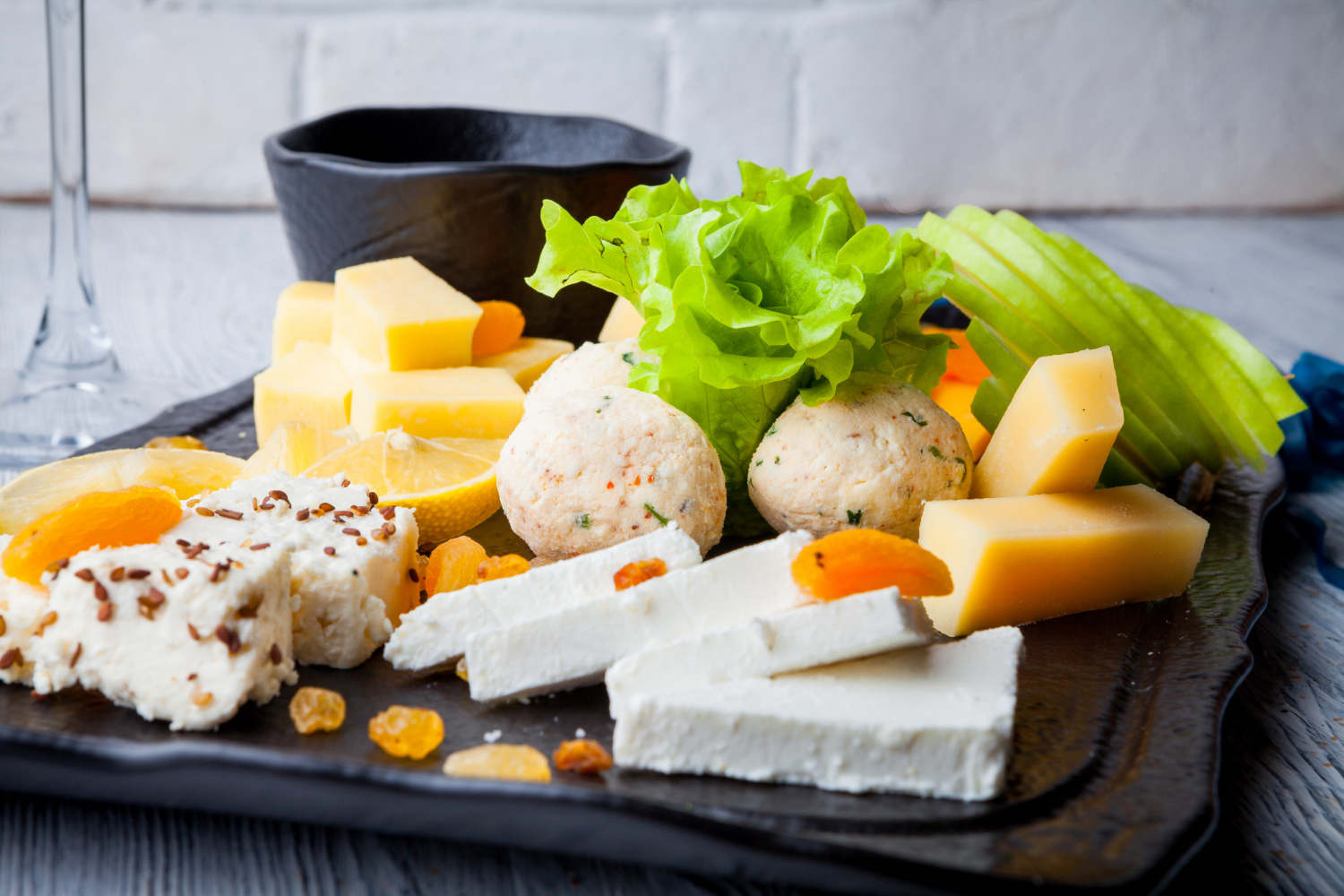 Plateau de fromages et fruits frais chez-basta à muret, assortiment gourmand sur assiette noire